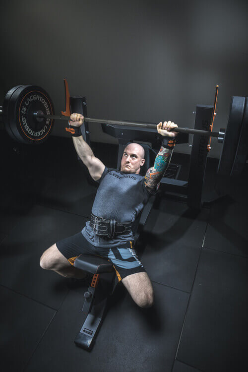 Hombre levantando una barra pesada en un banco en el gimnasio.