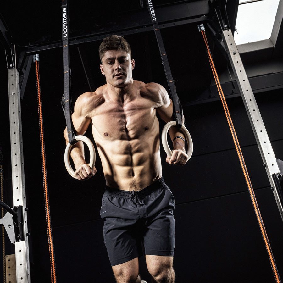Atleta durante un ejercicio de fondos en anillas de gimnasia Lacertosus, con correas ajustables 