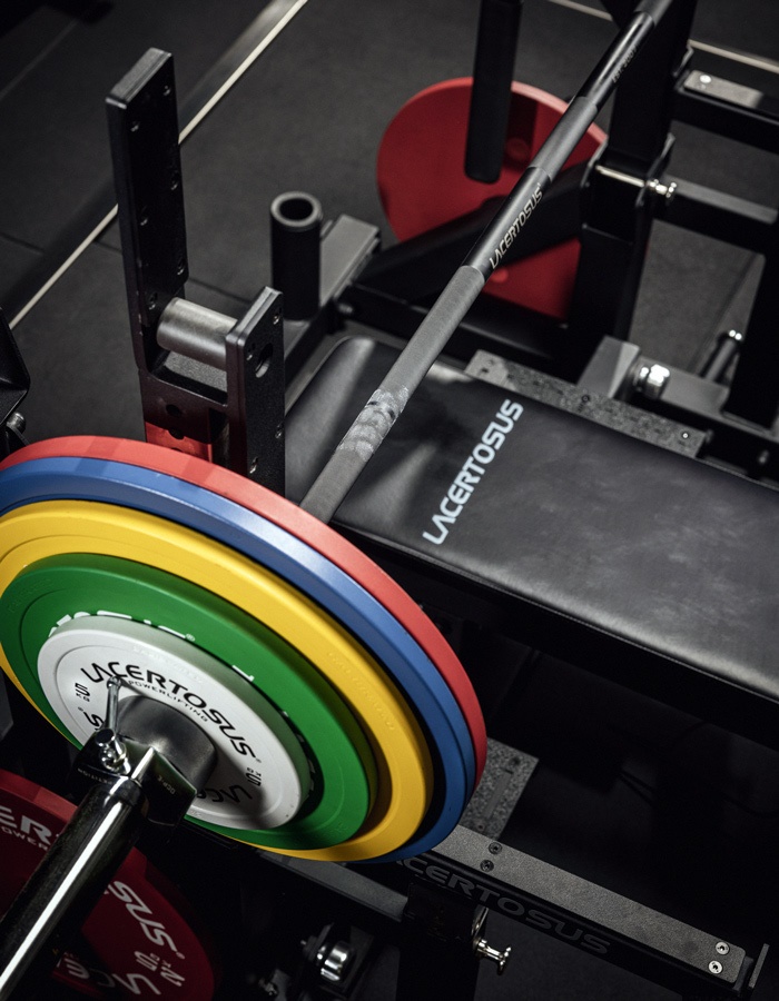 Bilanciere con pesi colorati su una panca da palestra Lacertosus.