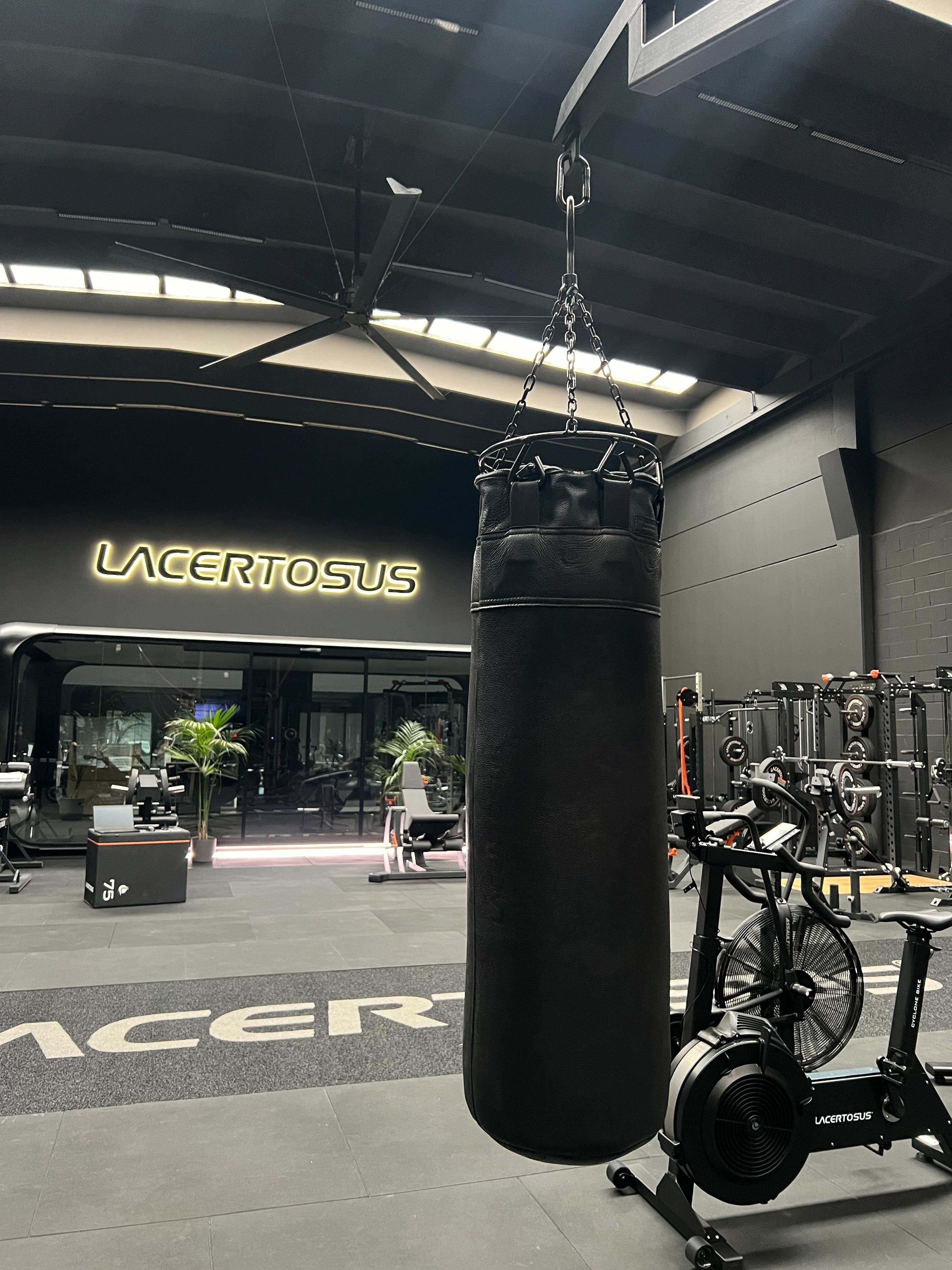 Gimnasio moderno con equipamiento fitness y saco de boxeo colgado.