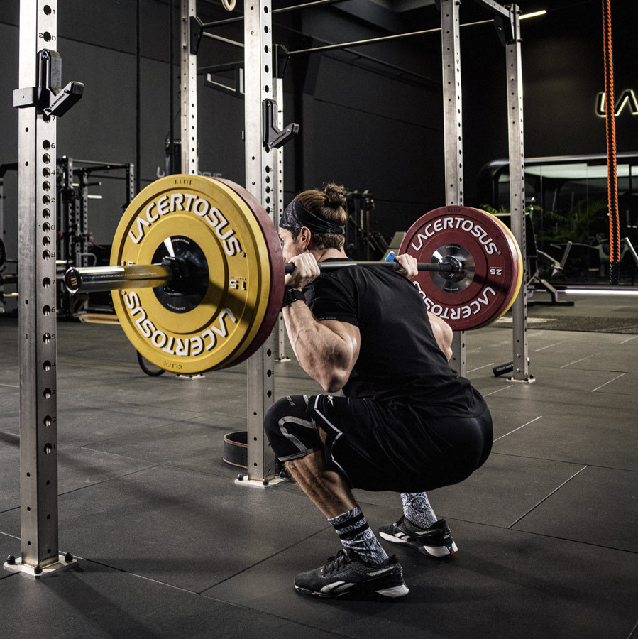 Persona que realiza una sentadilla con barra en el gimnasio.