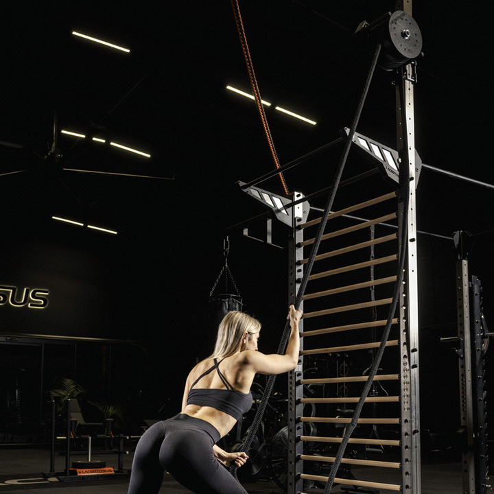 Femme s'entraînant avec des cordes ondulatoires dans une salle de sport.